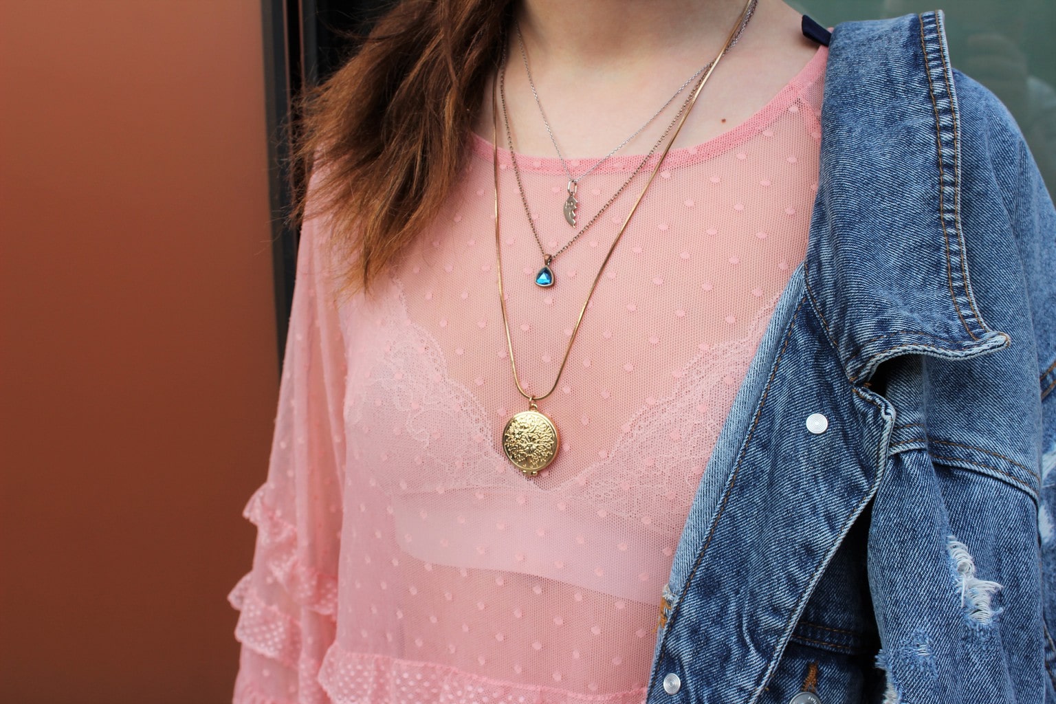 Barnard College student Francesca accessories her sheer, silky pink blouse with layered gold necklaces and a denim jacket.