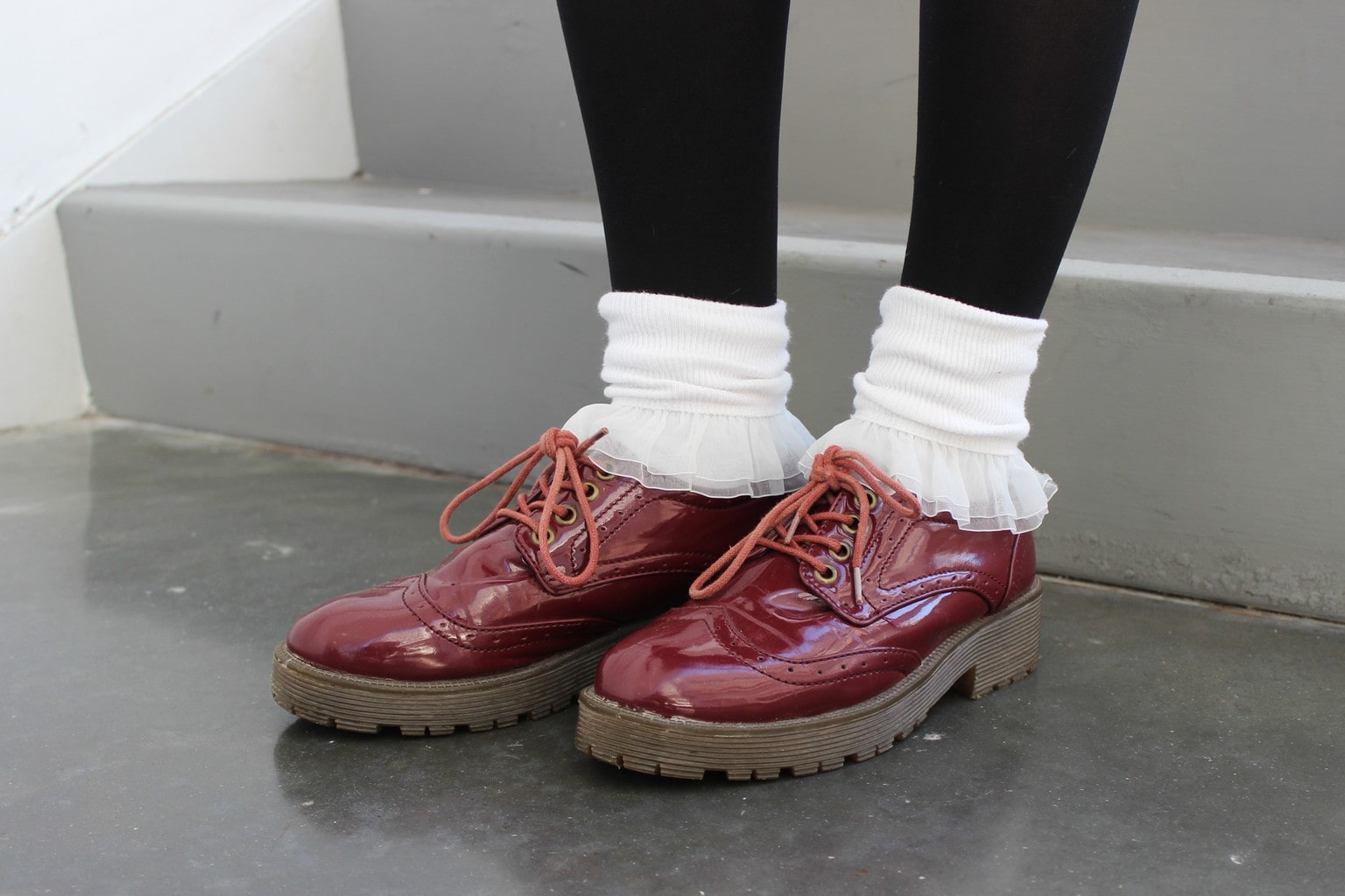 Hannah pairs white ruffled socks with chunky burgundy lace-up Doc Marten loafers.