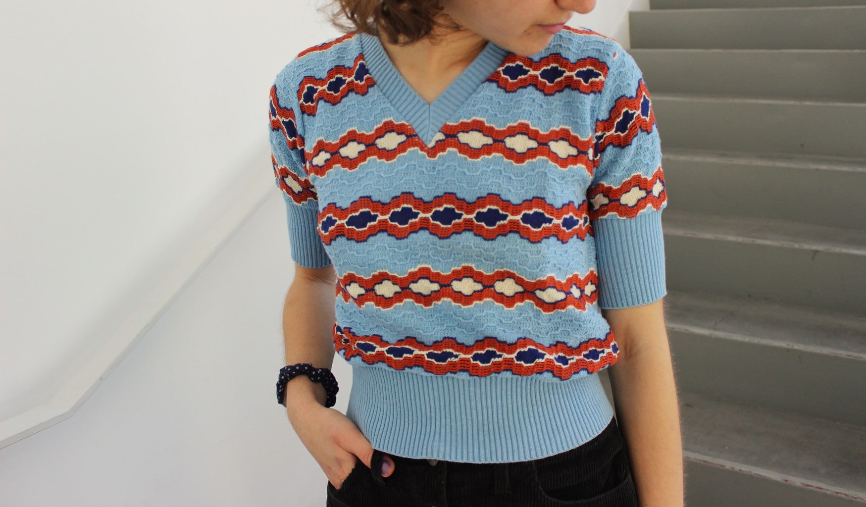 This baby blue short-sleeve sweater has a rustic red and white pattern.