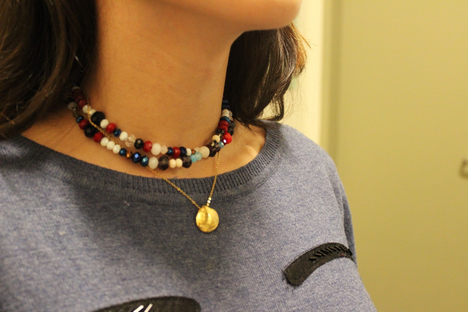 Rachel from Barnard College wears a layered beaded choker necklace with a gold pendant necklace on a delicate chain.