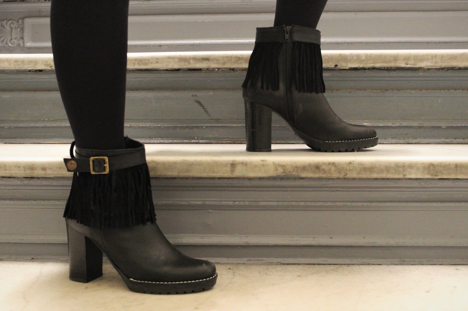 Black fringe heeled booties with gold buckles and chunky platforms.