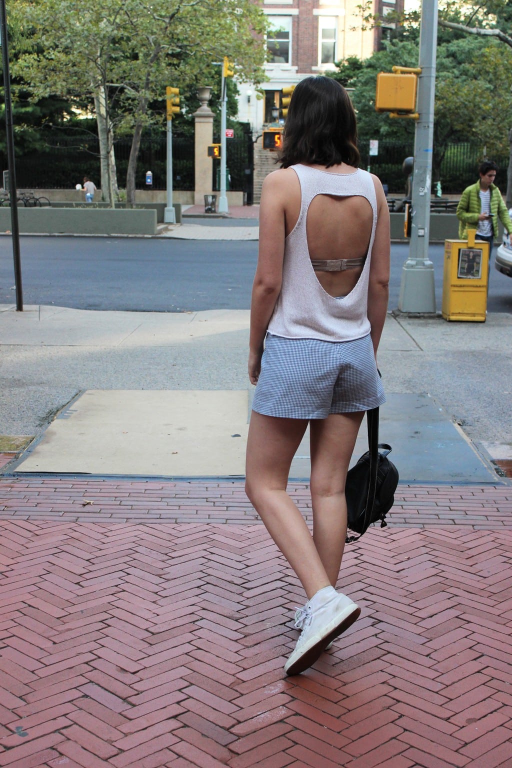 White knitted tank with open back worn with blue and white checkered gingham skort, shown as shorts from the back.