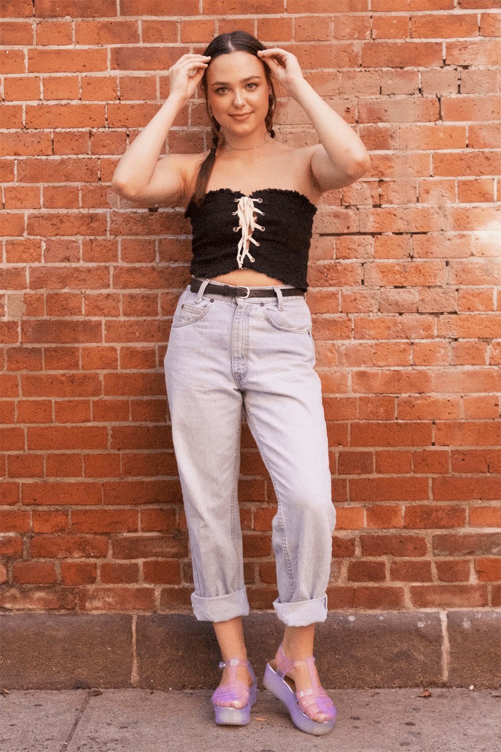 Student at Ball State University wears a lace-up strapless crop top with high-waisted and belted baggy jeans and jelly platform sandals.