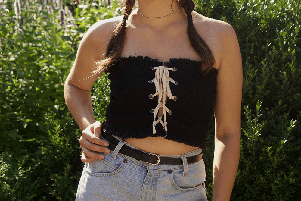 Lace-up crop top worn on a hot summer day with high-waisted mom jeans and a brown belt.