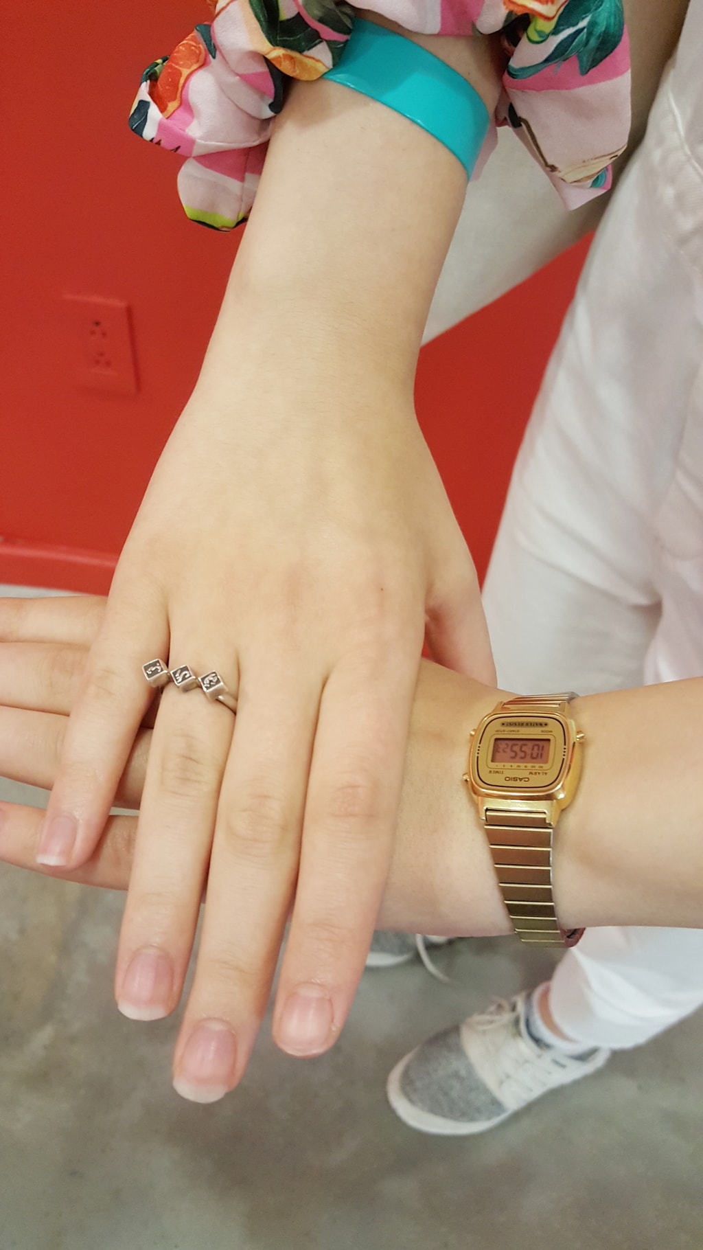 Simple gold details: a vintage gold analog watch and a delicate gold ring with three square black jewels.