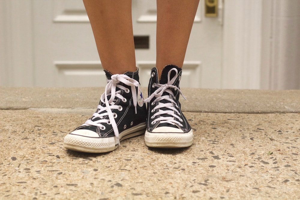 Classic black high-top Converse sneakers with bright white shoelaces.