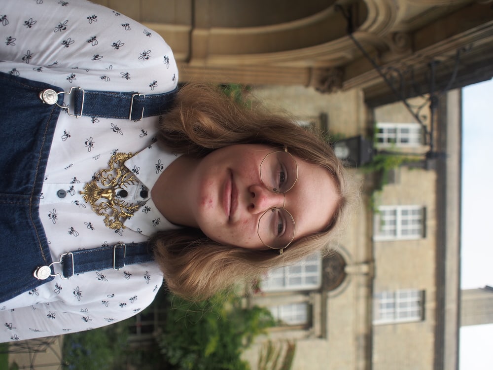 Hannah wears geometric gold wire-rimmed glasses.