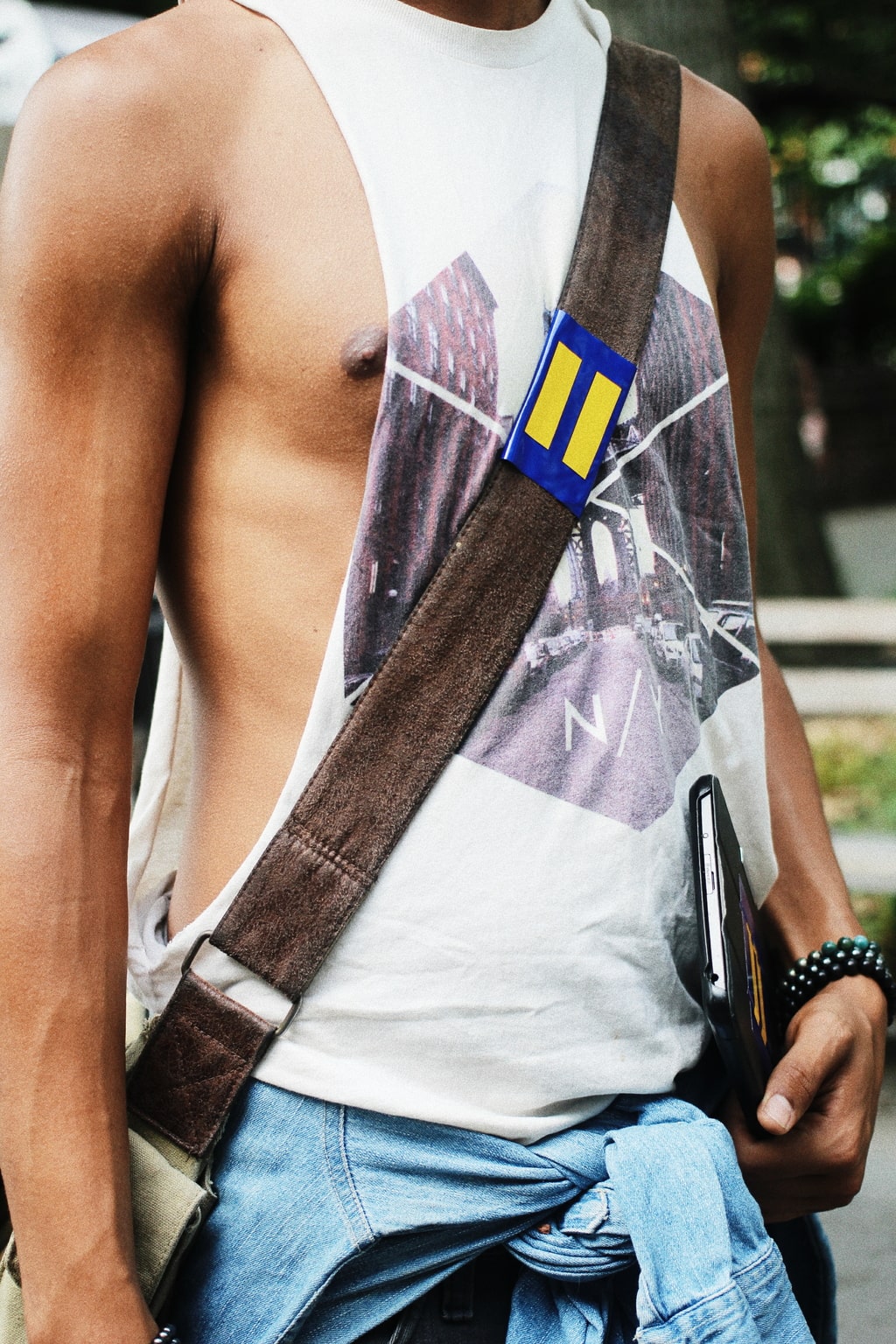 Campus trends at NYU: Student Kamron wears a muscle tank, messenger bag, and chambray shirt tied around his waist