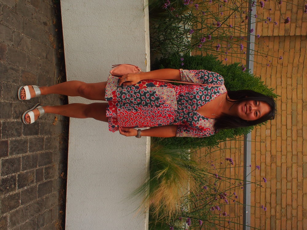 Sophie wears a mismatched print short sleeve v-neck blue, white, and pink dress with a ruffle hemline and simple flat sandals.