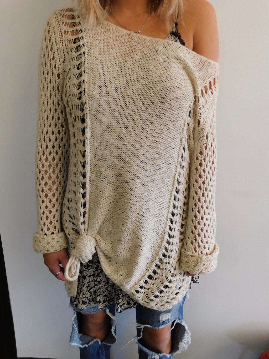 Lauren sports an oversized, casual oatmeal sweater with open weave arms and a black and white floral print camisole peeking out from underneath.