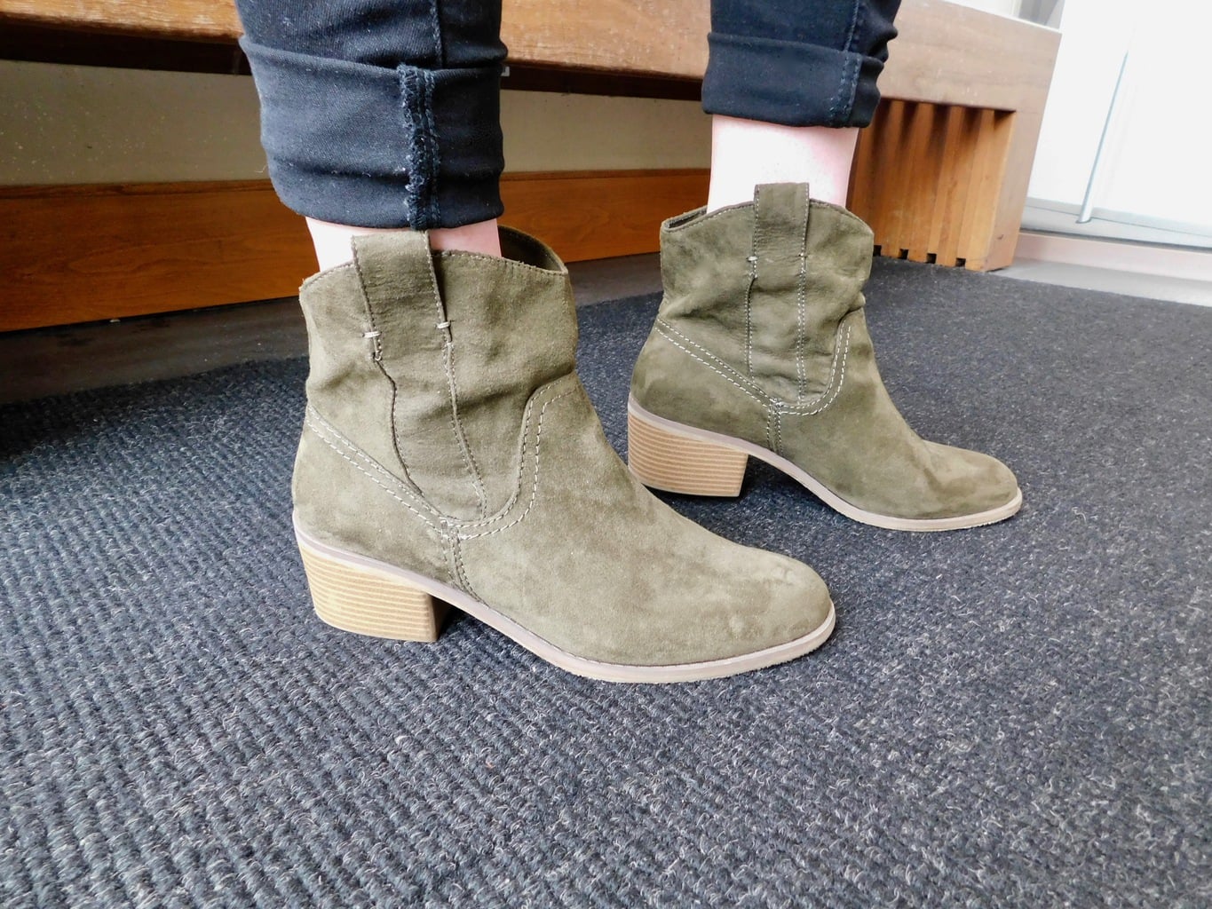 Jenna's olive green boots have a slight block heel and a Western flair.