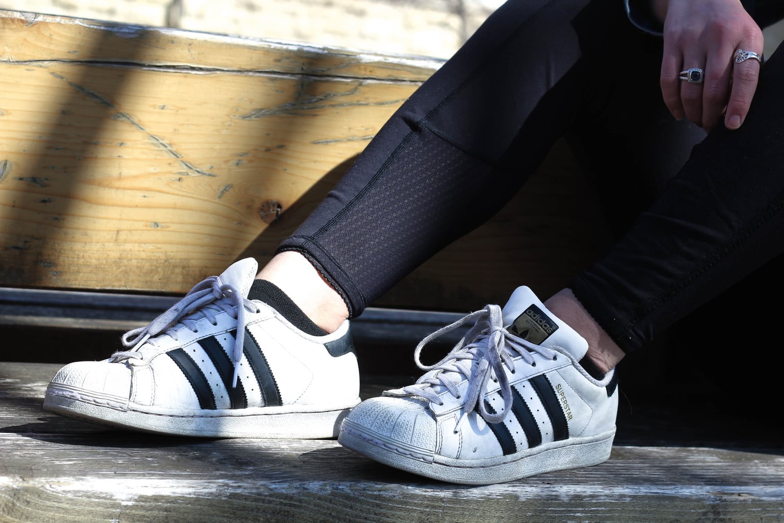 Bailey wears white and black worn-in Adidas all star sneakers with her athletic leggings.