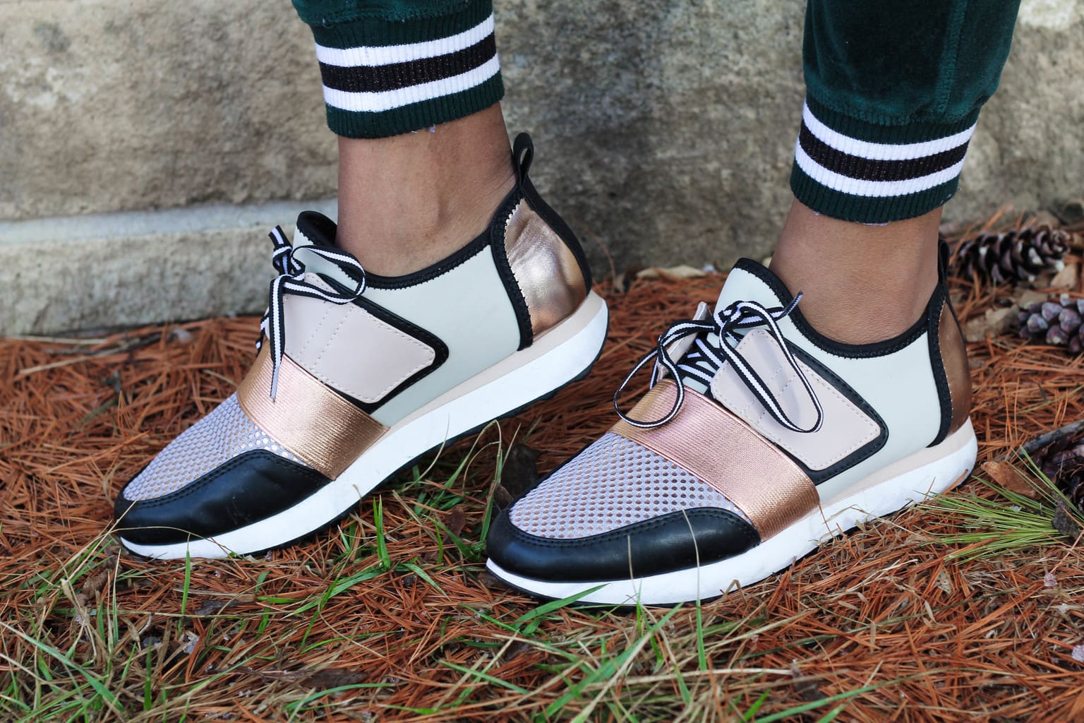 These black, white, and rosegold sneakers are extra trendy and fashionable, especially when paired with her emerald green velour jogger pants.
