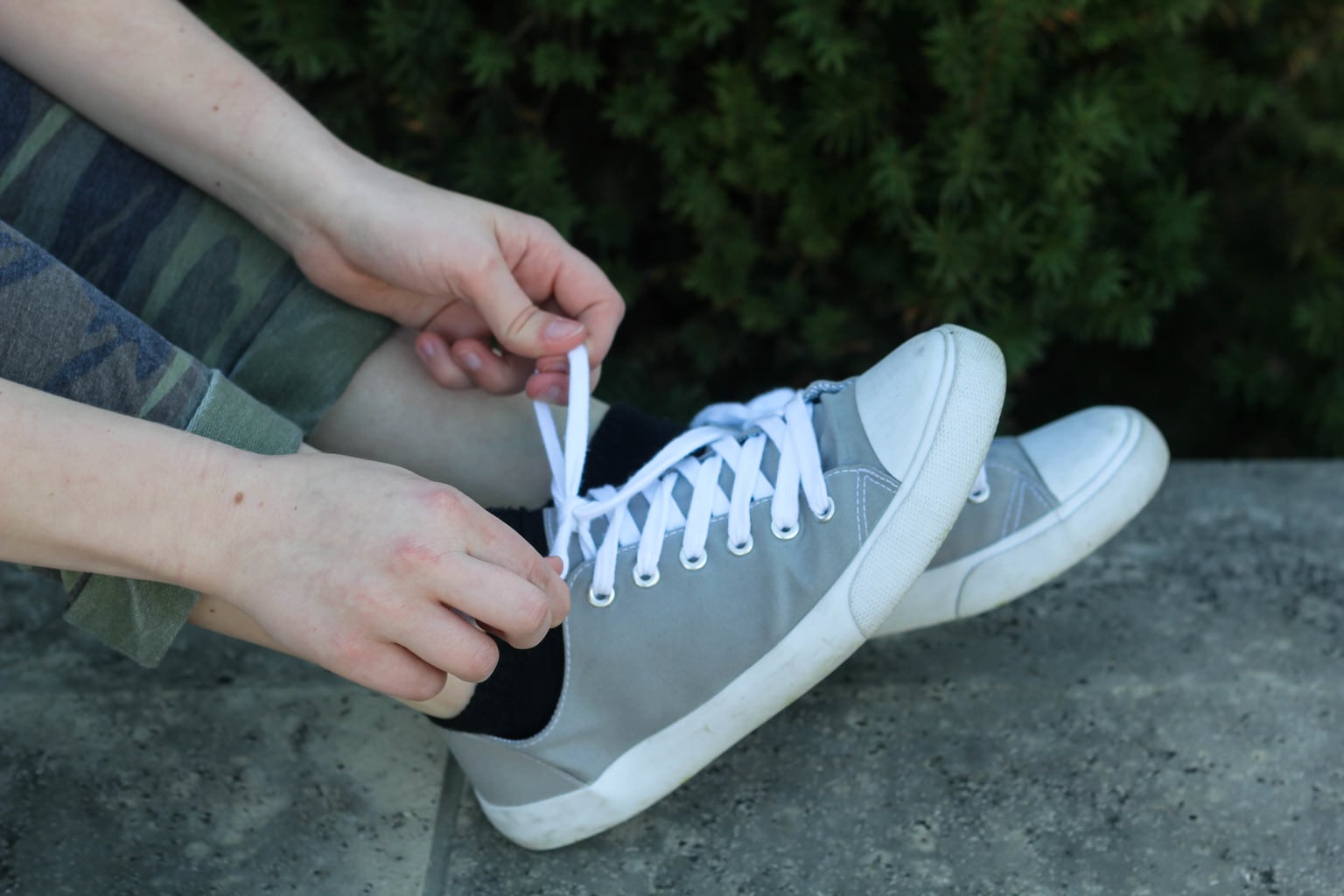 Monica wears her grey and white canvas sneakers with black ankle socks.