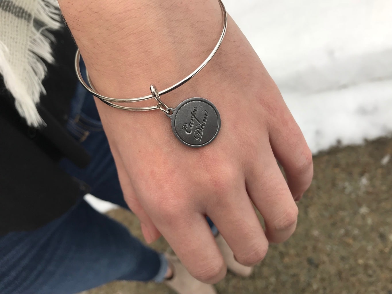 Erica wears a silver Alex & Ani bracelet with the inscription "Carpe Diem."