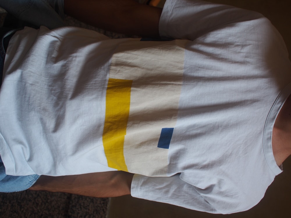 Andrea's simple crew neck white tee has a graphic bright yellow, muted yellow, and blue pattern on the front.