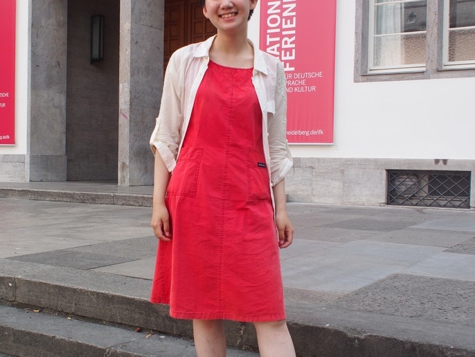 Victoria wears a boxy red vintage dress from Hong Kong with a sheer tan utility shirt on top.