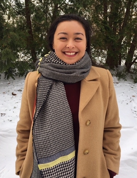 Shannon keeps warm in a black and white checkered blanket scarf, long tan peacoat, and burgundy turtleneck.