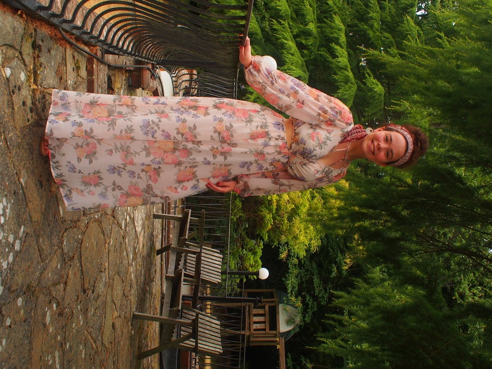 University of London student Amy in a long sleeve flowy floral print maxi dress, red bandana, and silver hoop earrings with cutout details.