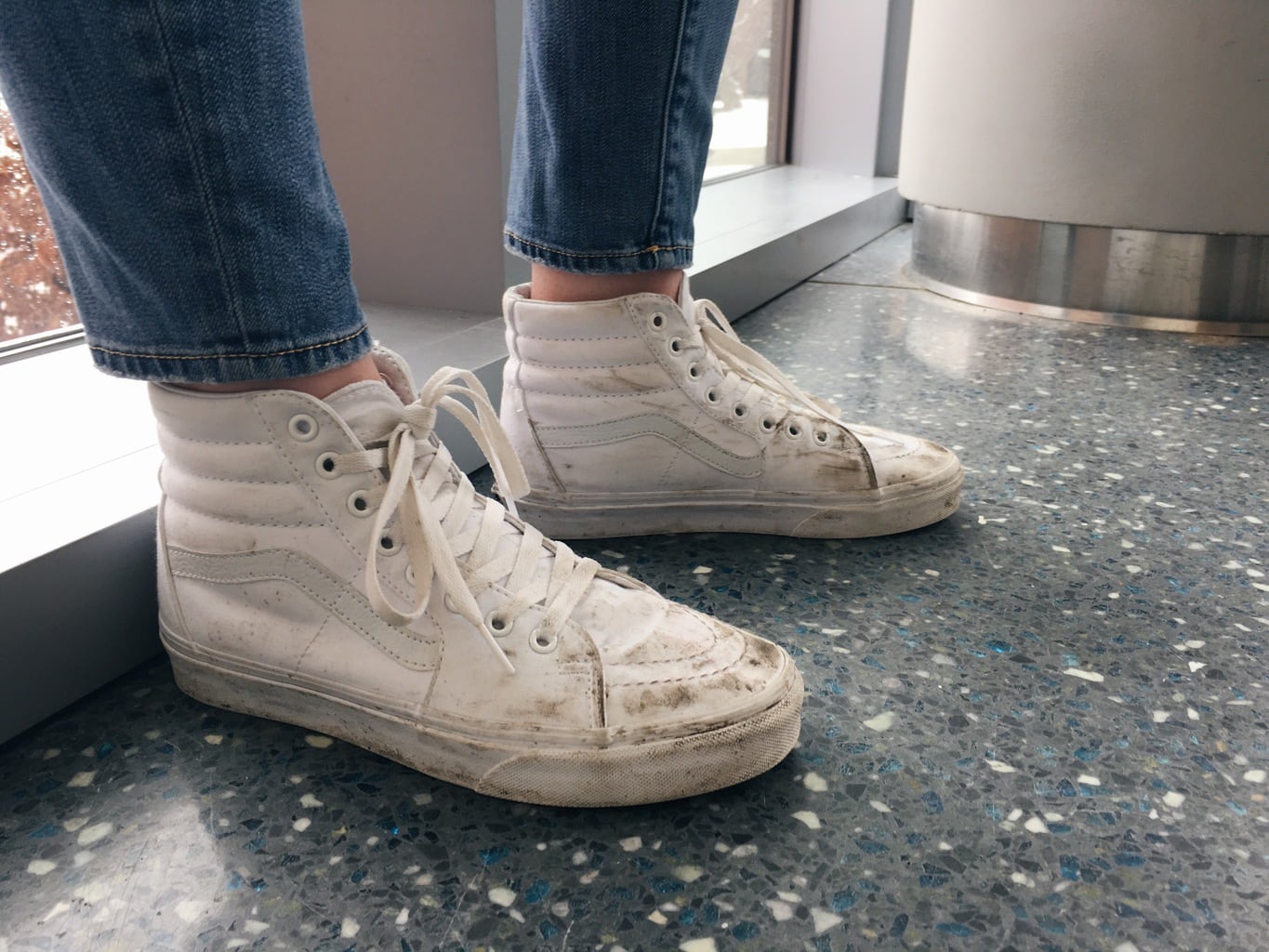 These high-top all white Vans lace-up sneakers are worn-in from walking across campus.