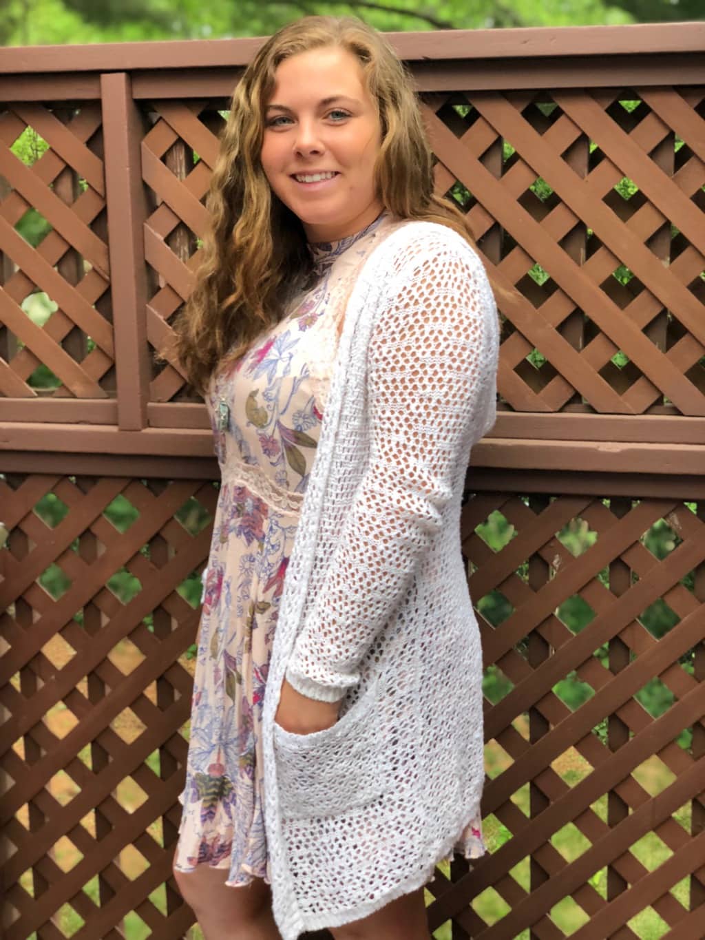 Hannah wears her white loose open-knit cardigan with a cream floral print dress.