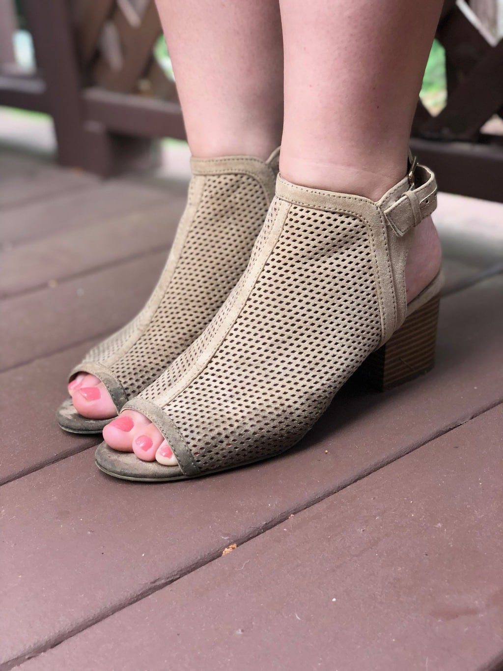 Hannah's taupe peep-toe heeled booties are chunky-heeled and have ankle straps.