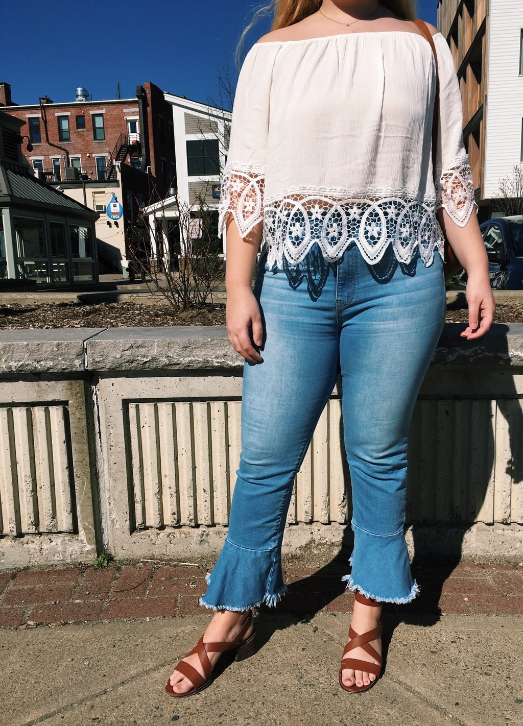 Kendall pairs her cream off-the-shoulder flowy lace top with cropped flare denim jeans and brown leather sandals.