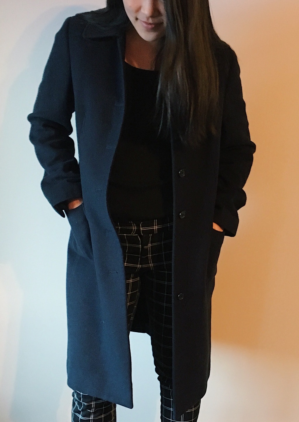 Yan Ni sports a long line navy peacoat with a black sweater top and black and white plaid pants.