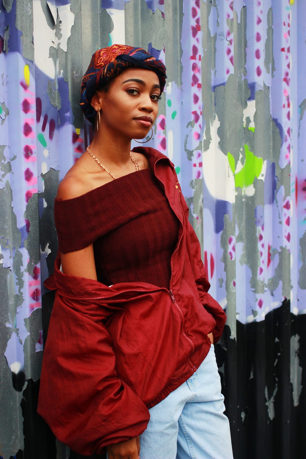 Student wears fall trends; oxblood off-the-shoulder top and matching windbreaker jacket, accessorized with vintage navy and maroon headscarf, gold hoop earrings, and simple gold necklace.