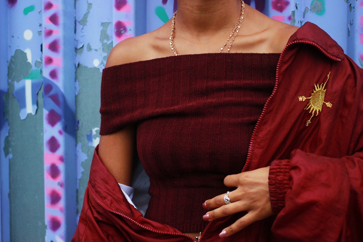 University of North Carolina student wears a matching maroon off-the-shoulder top and windbreaker with dainty gold jewelry accents.