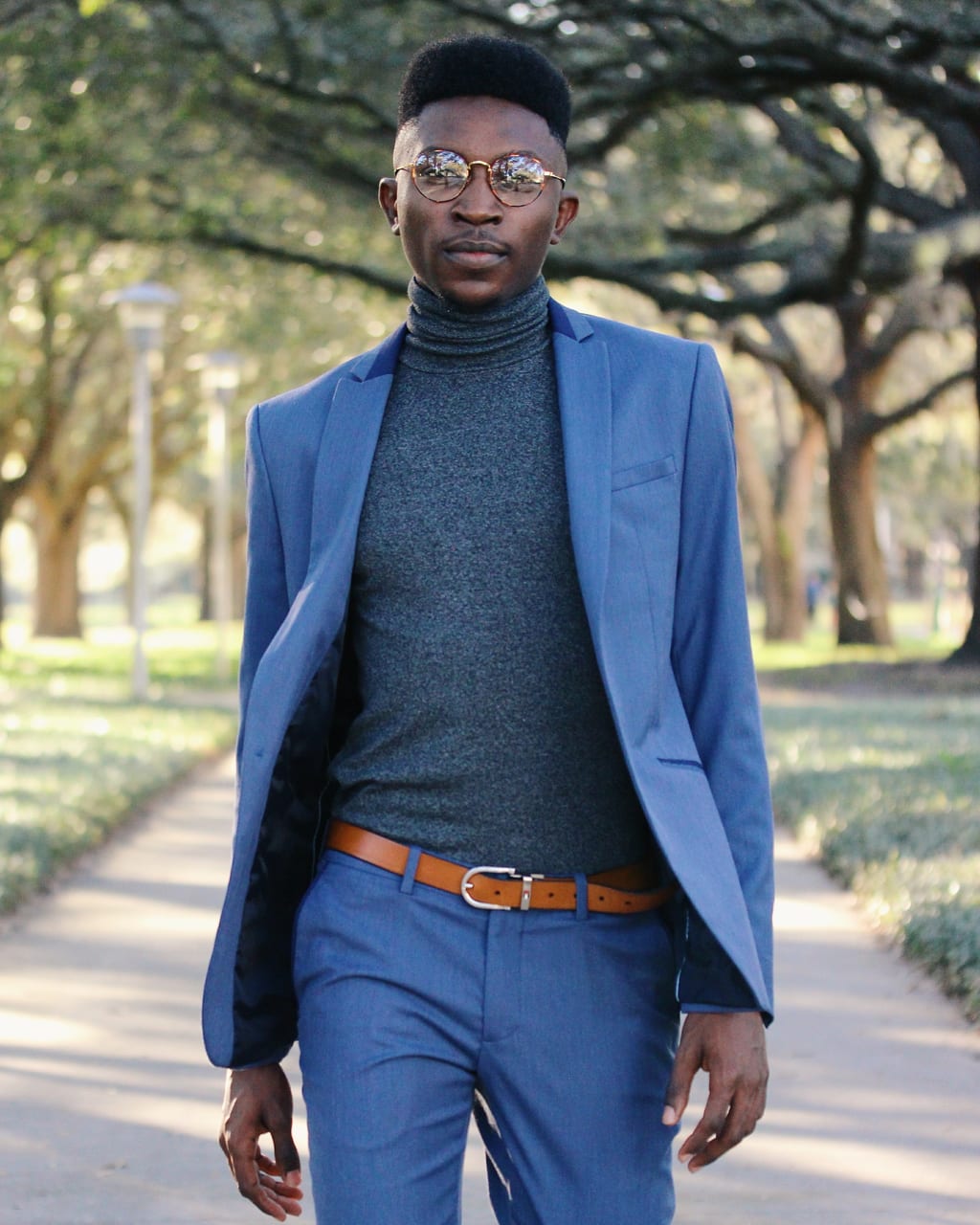 University of South Florida student Adedamola wears a slim fit blue Zara two-piece suit with a heather grey turtleneck and round tortiseshell glasses.