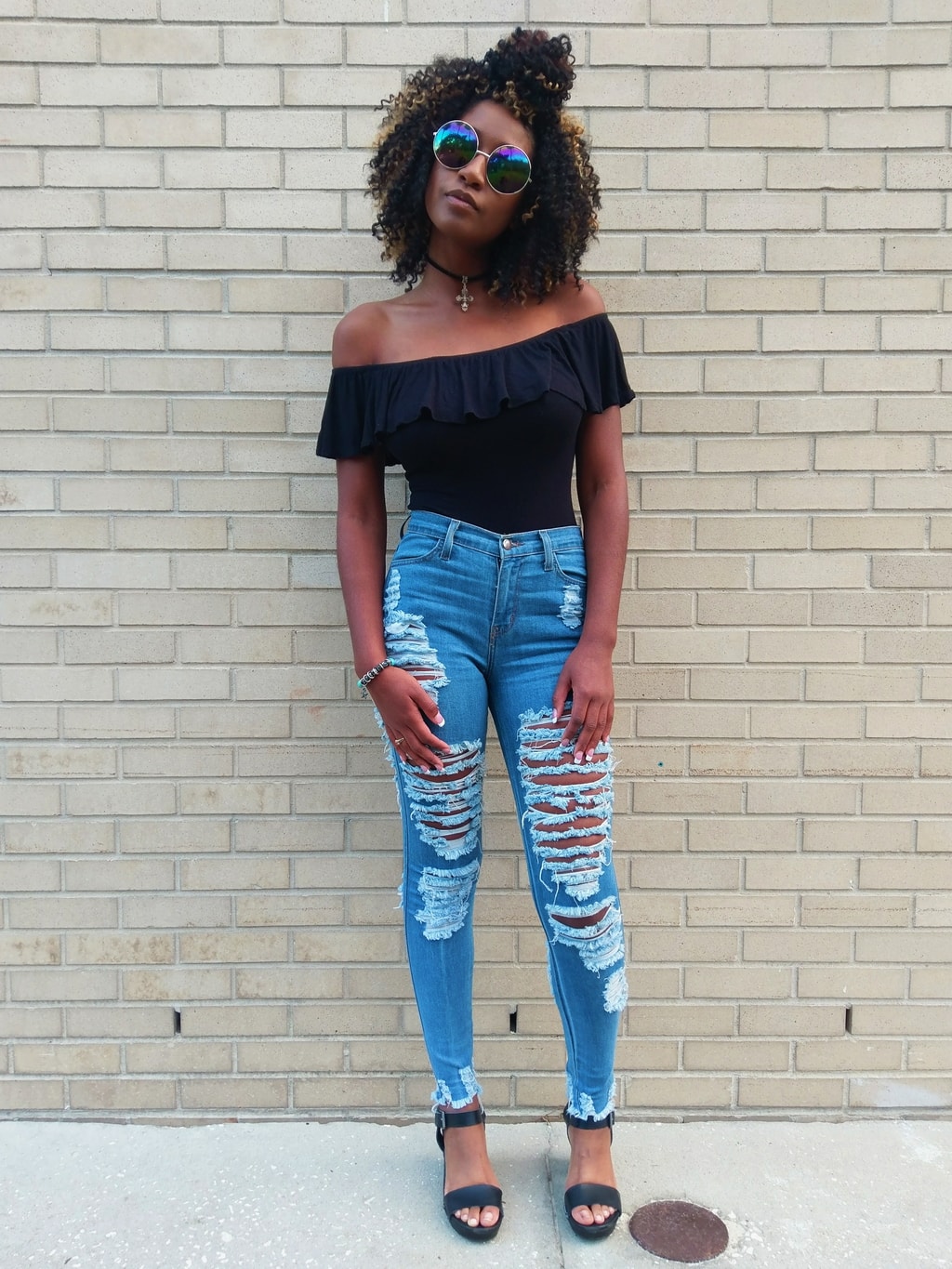 Payton, a University of South Florida student, rocks an 80-inspired look. Her off-the-shoulder black ruffled bodysuit tucks into her ultra shredded light-wash denim jeans. She polishes off her look with a cross choker necklace and ultra reflective round sunglasses.
