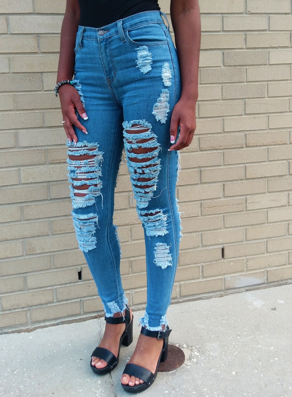 Payton wears ultra-shredded jeans with black chunky heeled sandals.