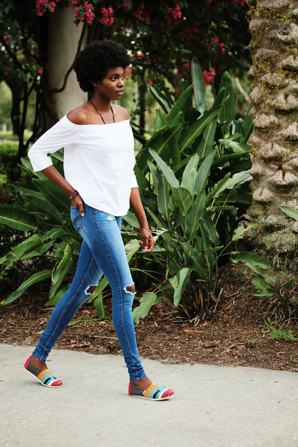 University of South Florida student Uchoku wears a simple white off-the-shoulder blouse with distressed light-wash jeans and colorful Toms shoes.