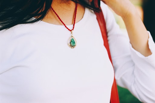 Pops of red: an heirloom jade stone pendant necklace encompassed by gold and a bright red chain.