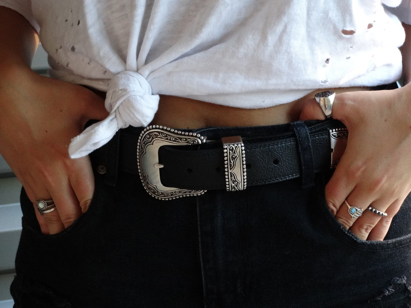 West Virginia University student wears black distressed denim shorts with a western-style black belt and silver belt buckle.