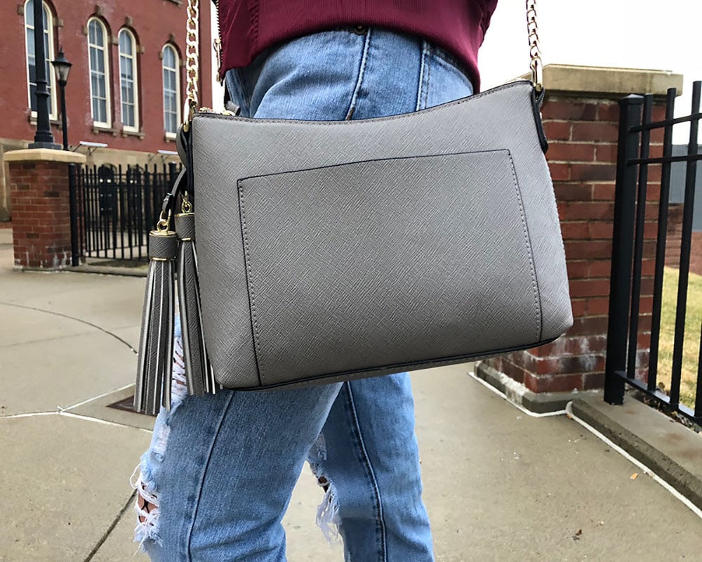 Courtni totes around a simple, crossbody grey purse with a gold chain strap and tassels.