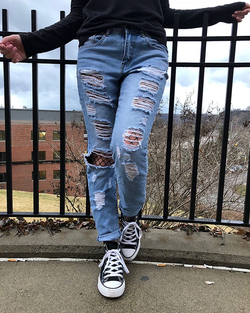 Courtni is punk in her shredded, light-wash denim jeans with black fishnets underneath and classic black Converse sneakers.