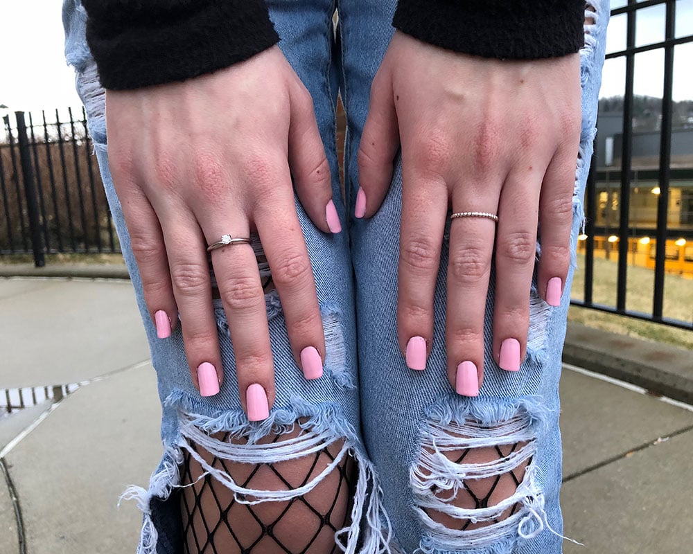 Courtni shows off her dainty silver rings with pastel pink glossy fingernail polish.