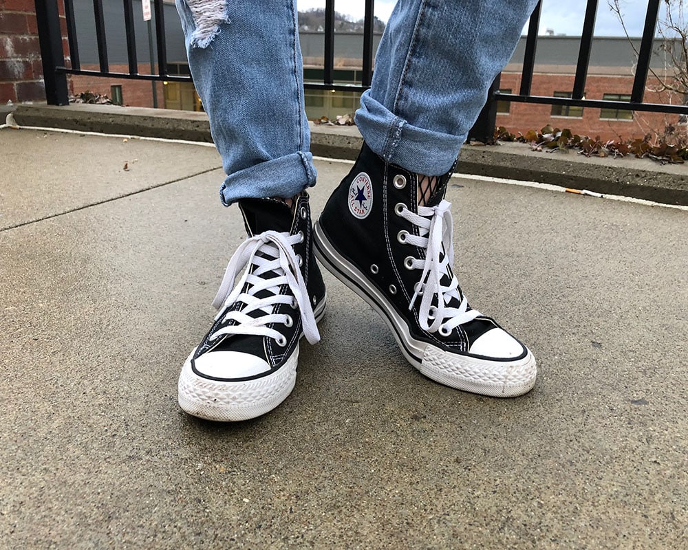 Courtni sports classic black Converse Chuck Taylors with her denim jeans rolled up to show off her fishnet tights.