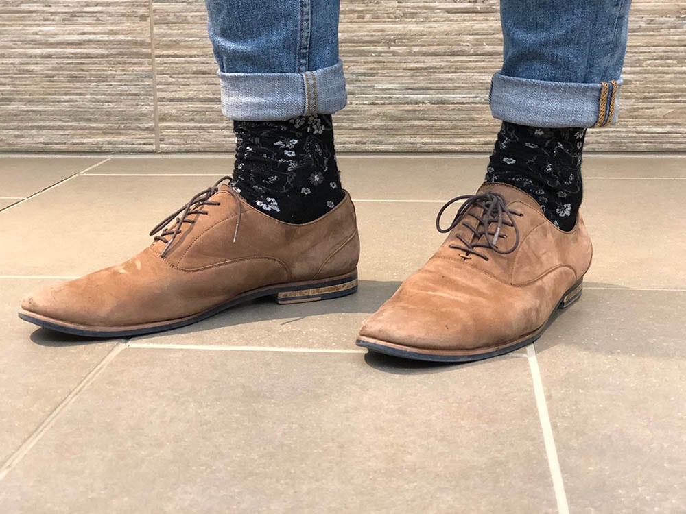 Davey sports brushed brown loafers with black patterned socks and cuffed jeans.