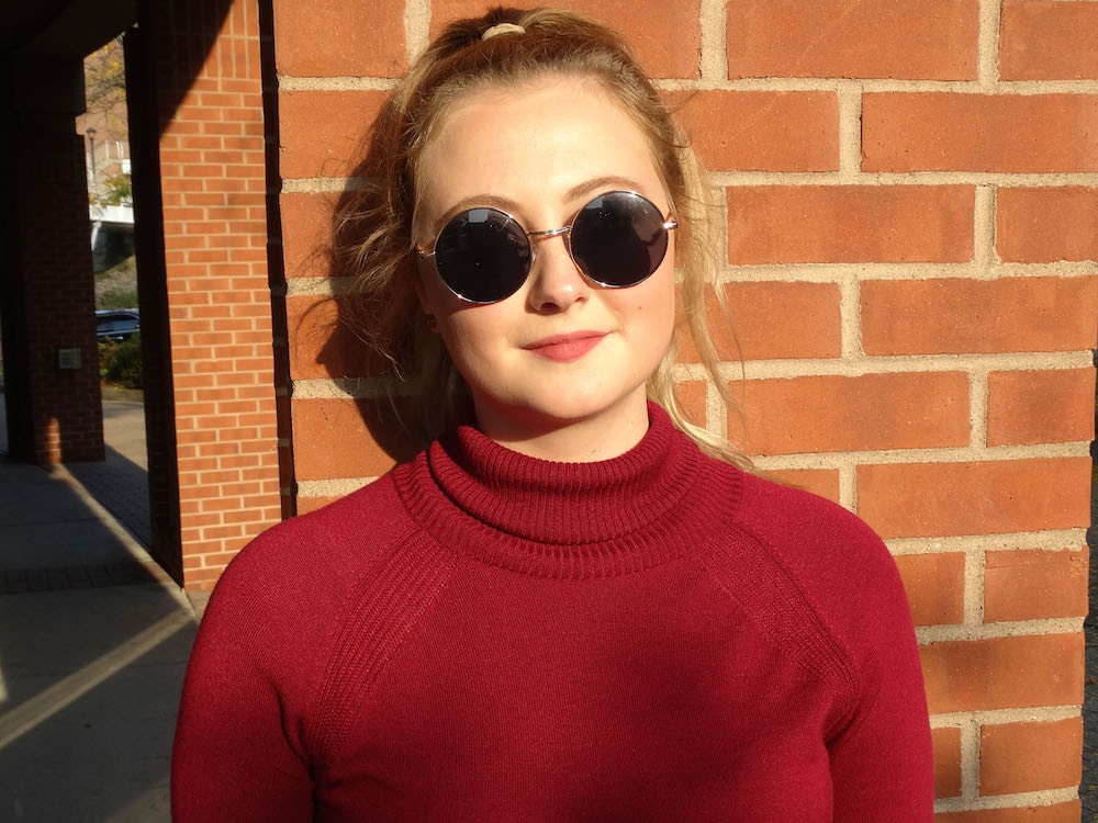 West Virginia University student wears circular JOhn Lennon sunglasses styled with a high ponytail.