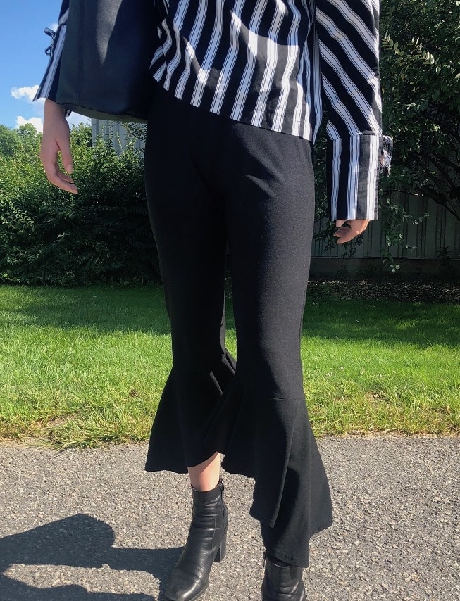 Georgia's pants are black cropped trousers with a ruffled flare.