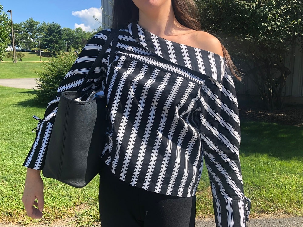 Georgia wears a black and white striped off-the-shoulder top with bell sleeves.