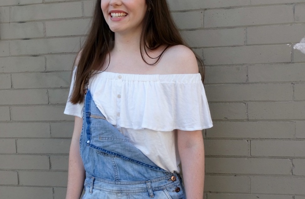 Off-the-shoulder white blouse pairs with light-wash denim overalls for a bohemian vibe.