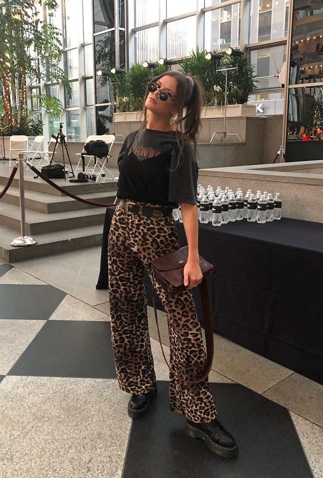 Hannah, a student at West Virginia University, wears a vintage Harley Davidson tee with a simple black cami over the top tucked into high-waisted leopard print flowy pants with a black and gold western belt.
