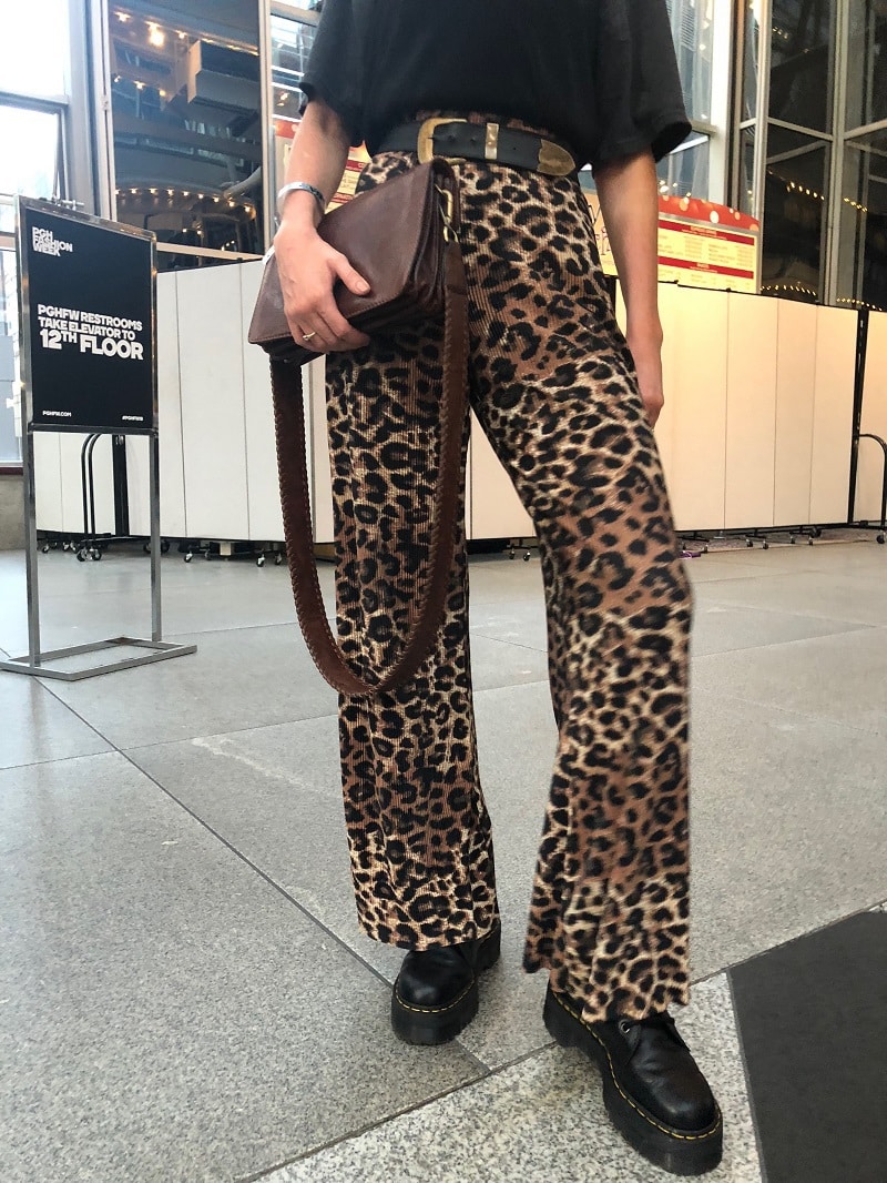 This WVU student wears flowy leopard print pants with platform doc martens, a brown leather purse, and a black and gold western belt.