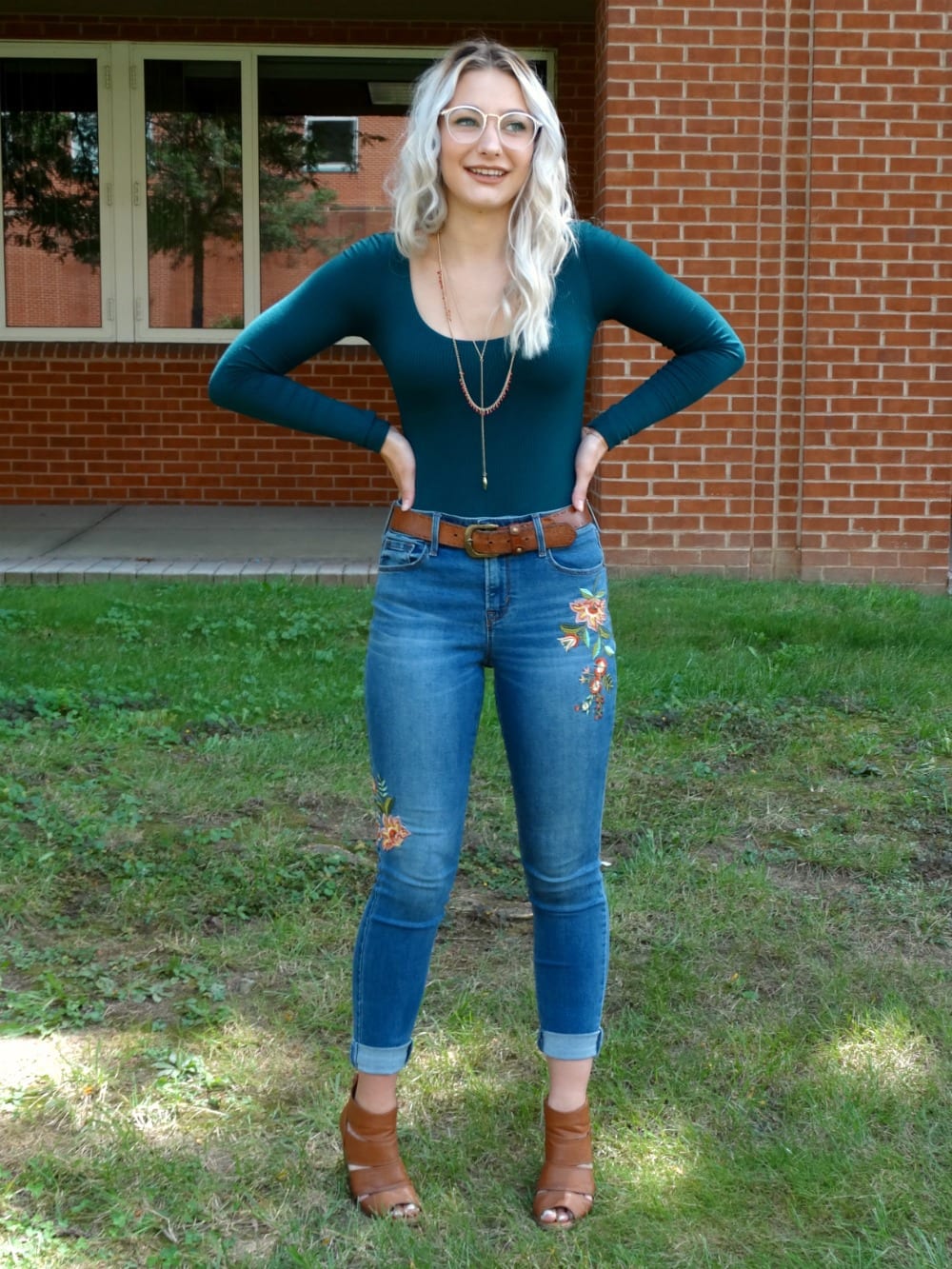 Student wears a long-sleeve scoop-neck bodysuit with a high-waisted pair of light-wash denim jeans and layered necklaces.
