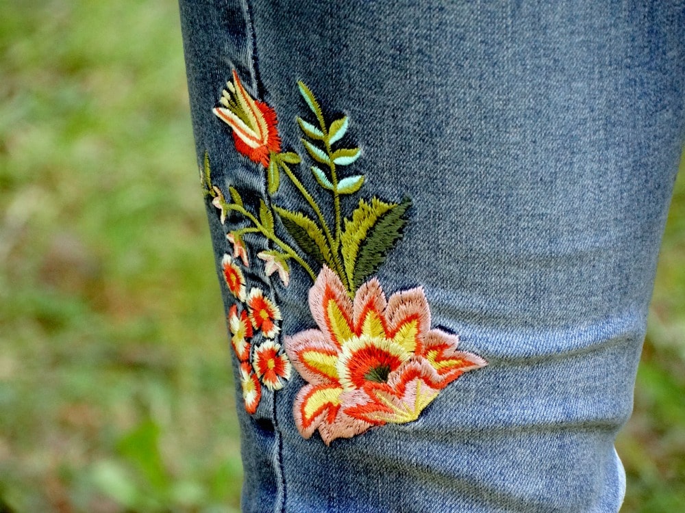 Light-wash denim embroidered with pink, yellow, and red flowers.