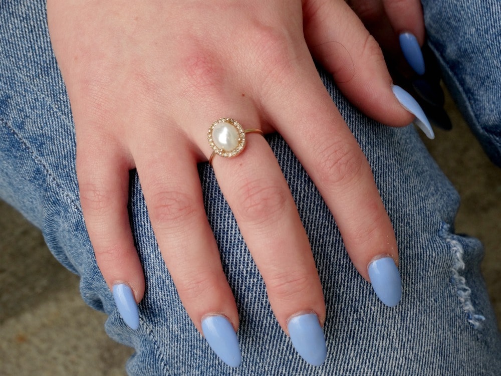 West Virginia University student wears baby blue fingernail polish on her long curved fingernails with a dainty gold and pearl ring.